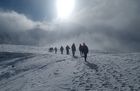 Die Oberstufe wandert durch den Schnee. Es hat ein Gemisch von Wolken und Sonne. Die Sonne kann sich knapp durchsetzen.