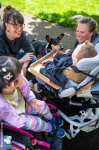 Der Kurzhaarcollie inmitten von zwei Schulkindern im Rollstuhl und zwei Betreuungspersonen